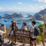 Wisatawan muda menikmati pemandangan bukit dan laut di Labuan Bajo Nusa Tenggara Timur yang masuk dalam daftar diskon tarif transportasi 2026.