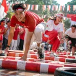 Peserta mengenakan pakaian merah putih sedang berlomba dalam acara peringatan 17 Agustus.
