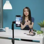 Handphone dengan dashboard TikTok affiliate dan perlengkapan kreator konten di atas meja kerja modern.